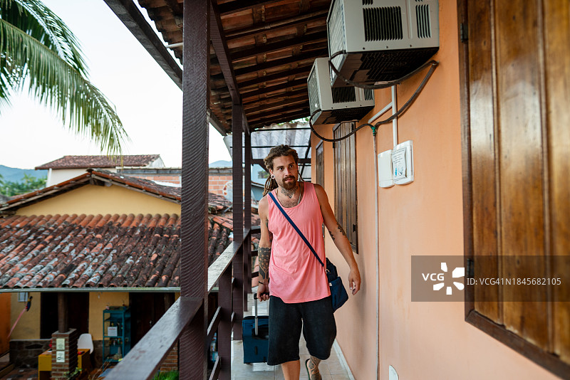 年轻男人携带行李抵达度假村图片素材