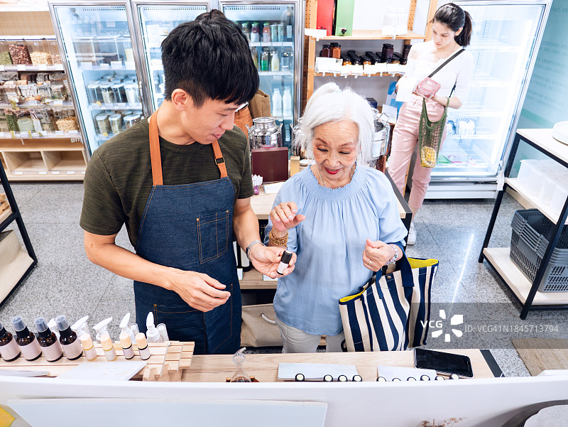 员工在无包装商店热情帮助老年女顾客图片素材
