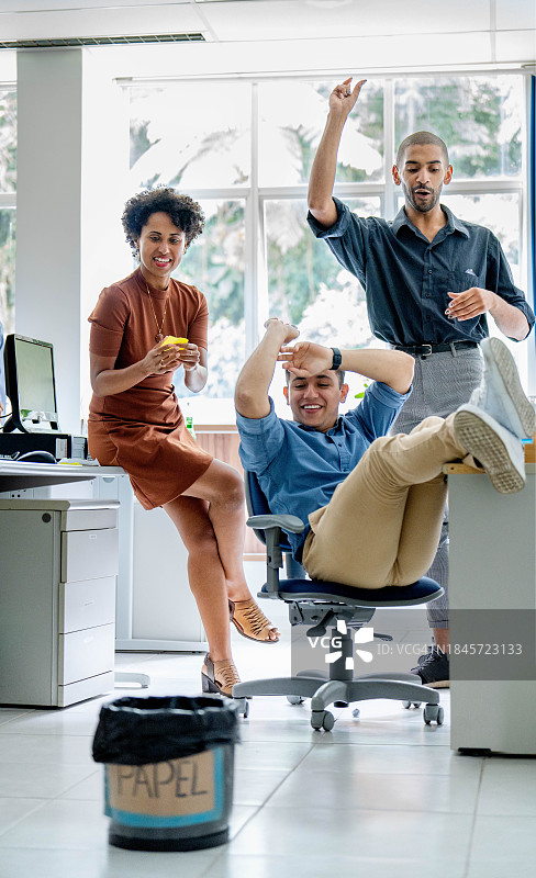 办公室聚会期间玩扔纸游戏的商务人士图片素材