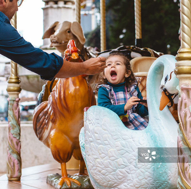 在旋转木马上，父亲给女儿冰淇淋图片素材
