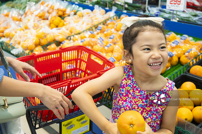 小女孩和母亲在超市挑选橙子图片素材