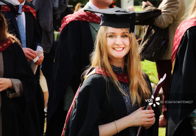 自豪、微笑和快乐的年轻女子从她的硕士毕业典礼上出来时微笑图片素材