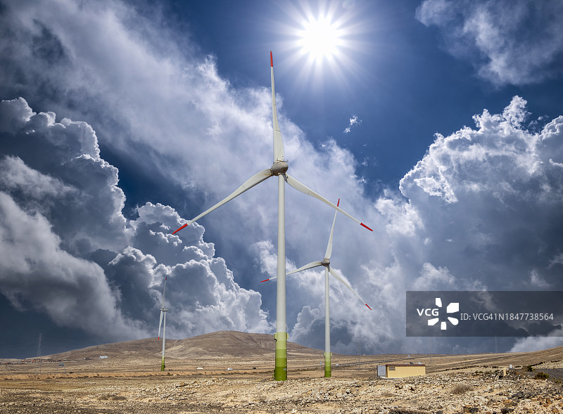 阳光明媚的暴风雨天空下的沙丘风车图片素材