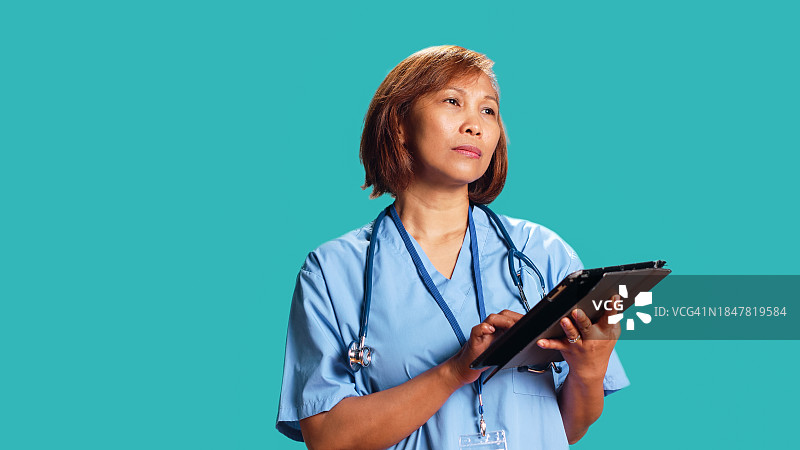 女医生在蓝色背景下手持剪贴板图片素材