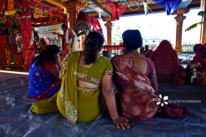 女性在印度教寺庙中观察一位牧师向神灵祈祷。图片素材