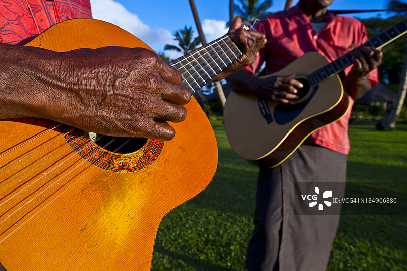 音乐家们在热带岛屿的日落时分演奏原声吉他。图片素材