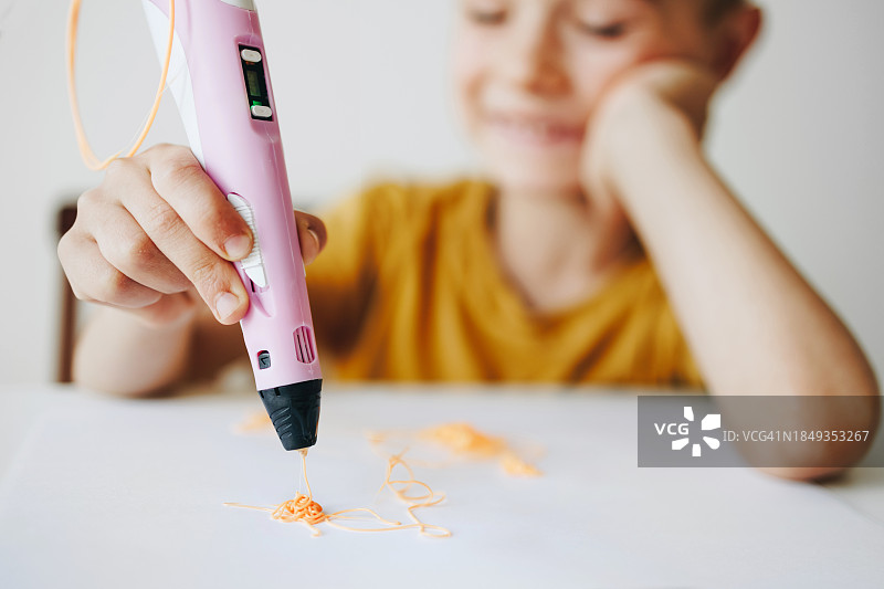 儿童男孩在白色桌子上使用3D打印笔创作图片素材