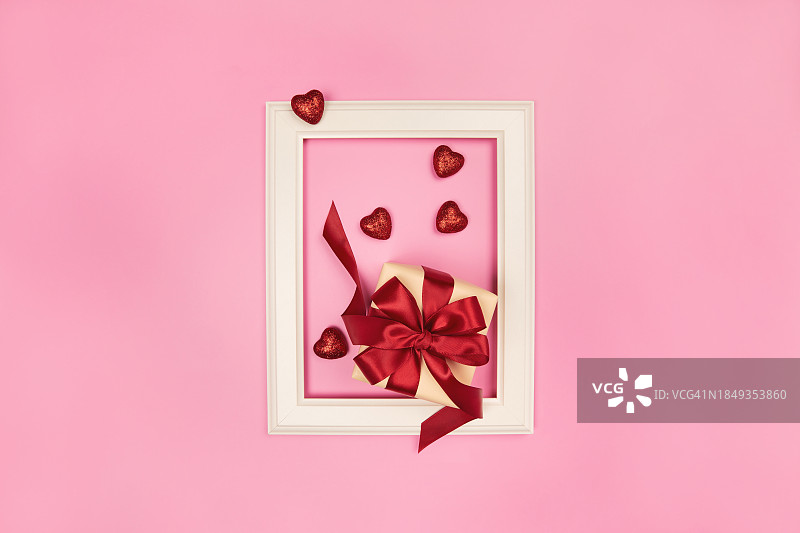 红色爱心、圣诞、新年、情人节、母亲节礼品盒与白色相框创意排版，粉色背景图片素材