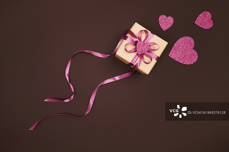 圣诞节、新年、情人节、母亲节礼物和粉红色闪亮的心在深巧克力棕色背景上，带有文本复制空间。平放，顶视图图片素材