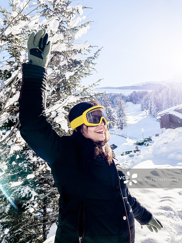 拉丁美洲女性在阳光明媚的法国阿尔卑斯小镇享受冬季仙境图片素材