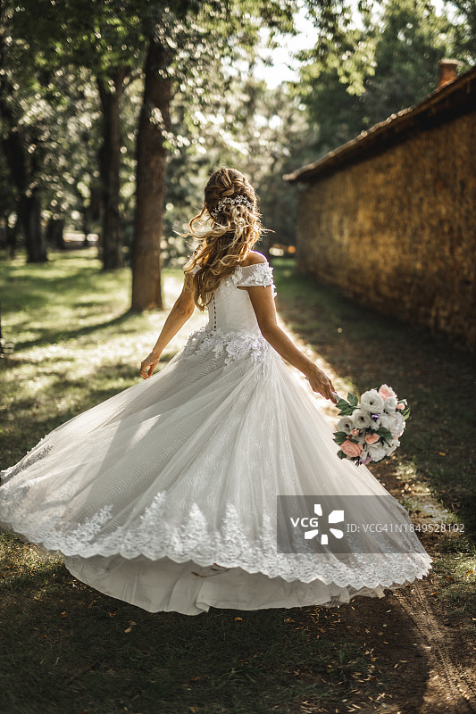 新娘在绿色田野上旋转婚纱的背影图片素材