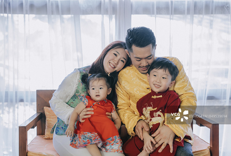 中国年轻家庭坐在沙发上庆祝中国新年，祈求好运、繁荣和健康图片素材