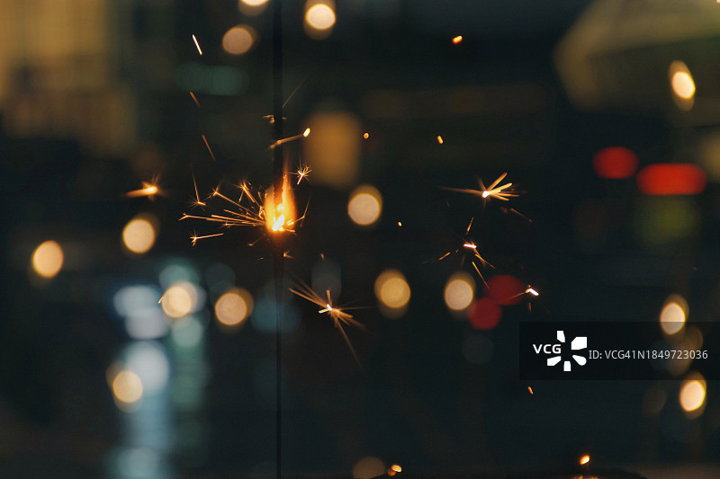 城市灯光黑暗背景下的燃烧的孟加拉火焰图片素材