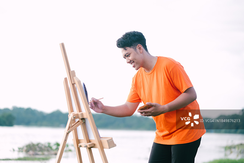 快乐的亚洲青年男子户外绘画图片素材