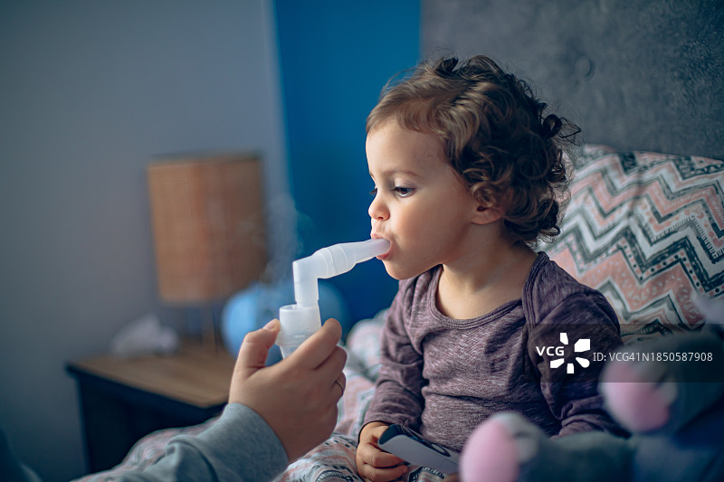 母亲帮助小女儿用雾化器做雾化图片素材