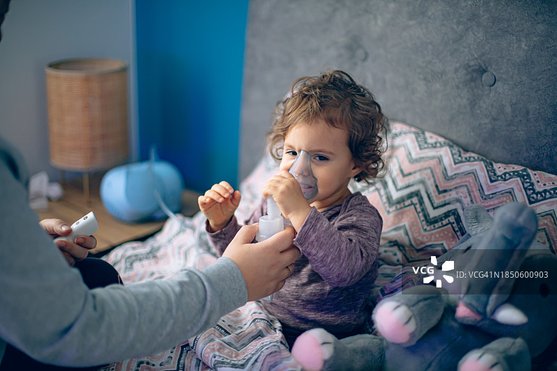母亲帮助小女儿用雾化器做雾化图片素材