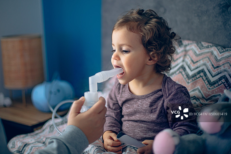 母亲帮助小女儿用雾化器做雾化图片素材