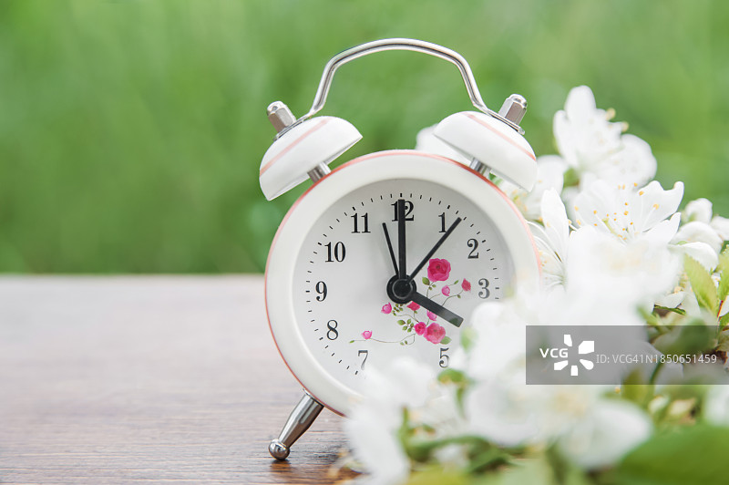 木质背景上的闹钟和开花的树枝图片素材