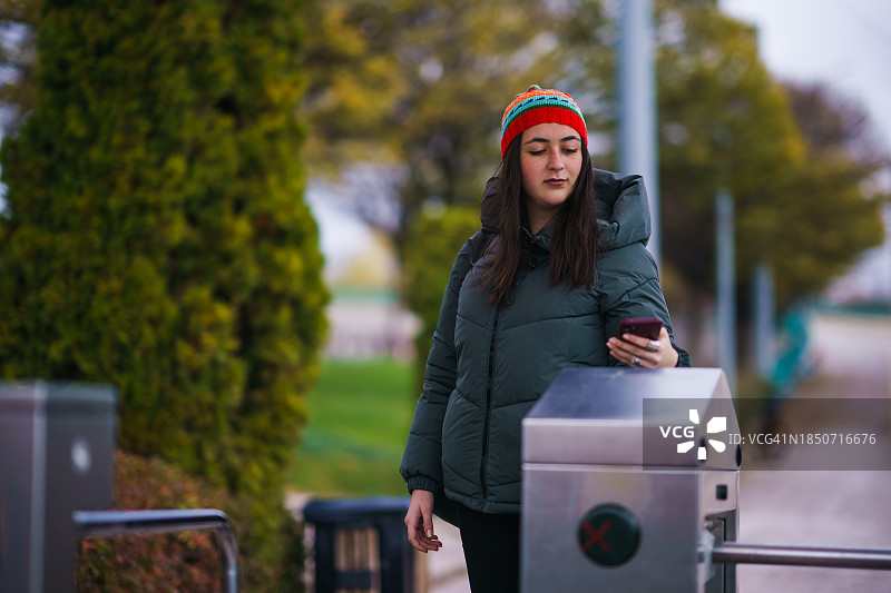 年轻女人在有轨电车站使用手机图片素材