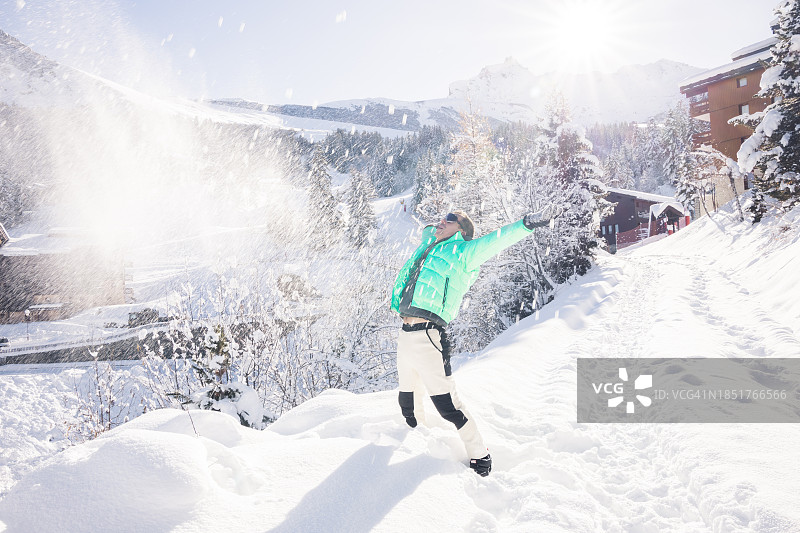 在法国阿尔卑斯山享受冬季仙境，抛洒新鲜雪粉的男人图片素材