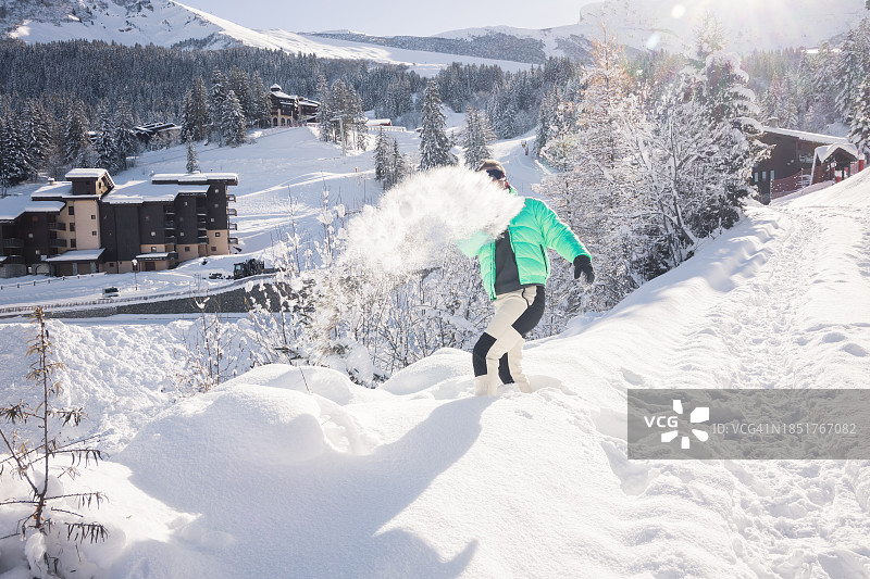 在法国阿尔卑斯山享受冬季仙境，抛洒新鲜雪粉的男人图片素材