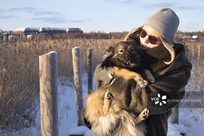 在阳光明媚的冬日里与她的狗在自然中玩耍的女人图片素材