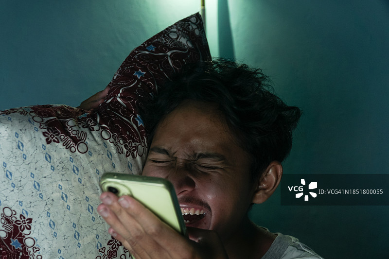 青年男子靠在枕头上大笑图片素材