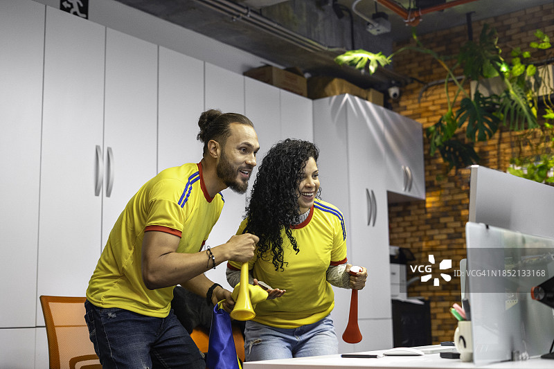 同事在办公室的电脑上观看足球比赛图片素材