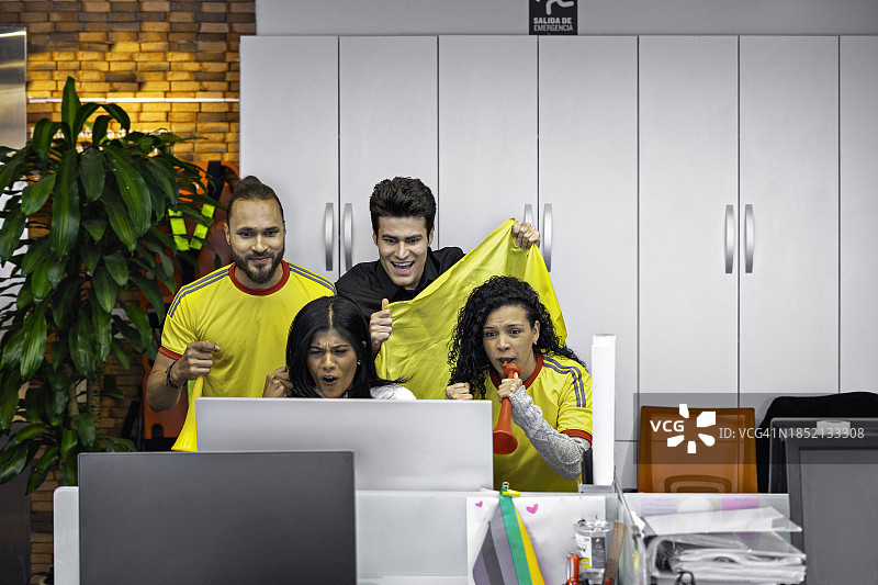 同事在办公室的电脑上观看足球比赛图片素材