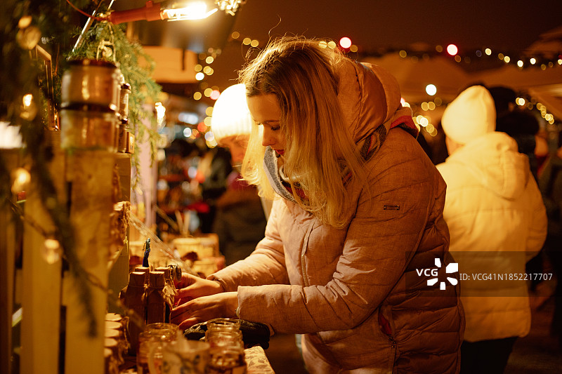 在热闹的街头市场中，迷人的女顾客驻足欣赏果酱罐图片素材