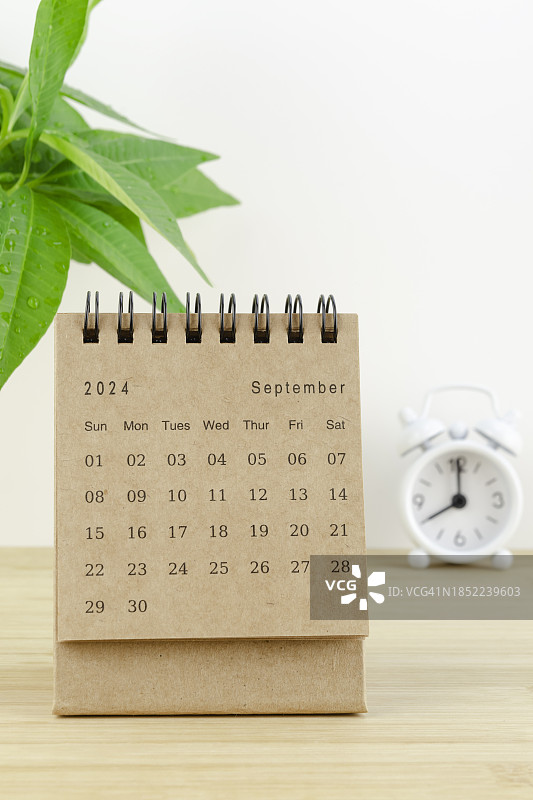 2024年台历：九月日历，用于规划每日工作和生活，工作台上有室内植物和闹钟。图片素材