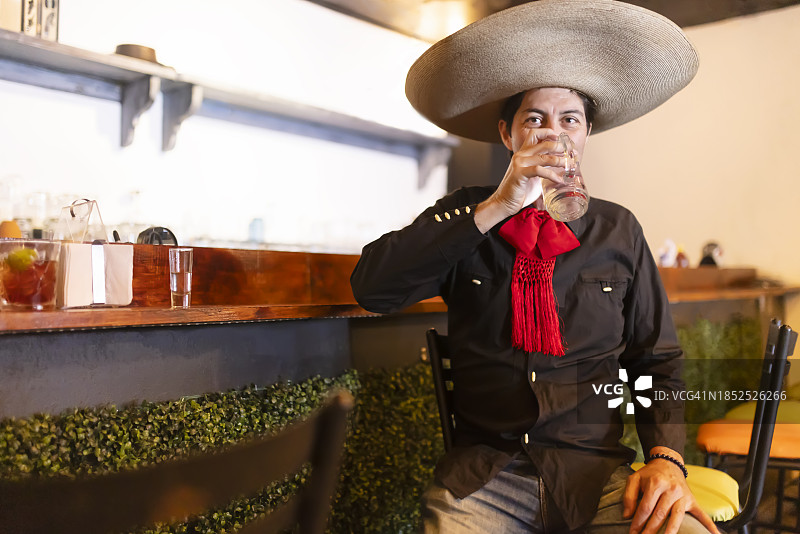 戴着墨西哥帽的男子正在用罐子喝水图片素材