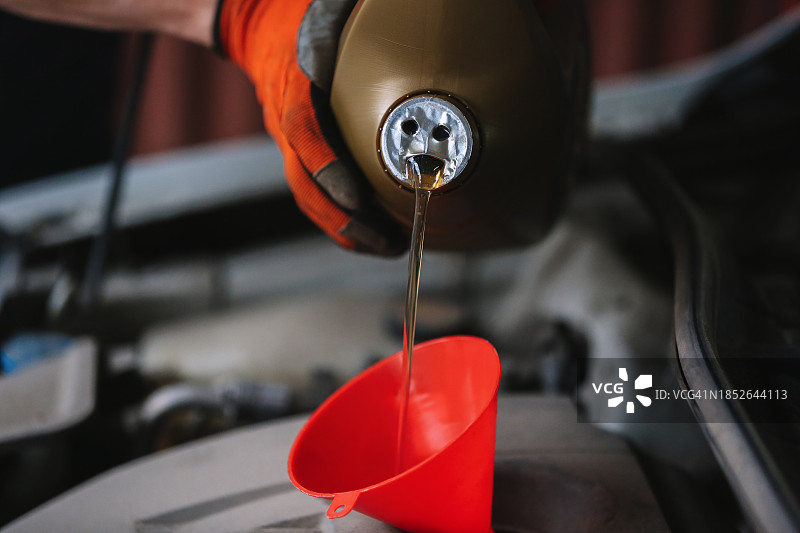 关于危机的幽默内容。将汽车机油倒入发动机，使用红色漏斗并从中获得乐趣图片素材