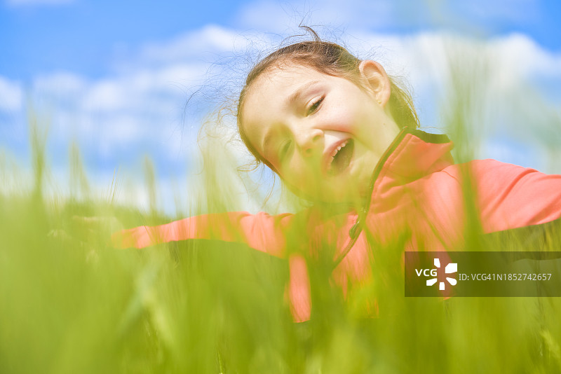正面视角：藏在草丛后微笑的女孩图片素材