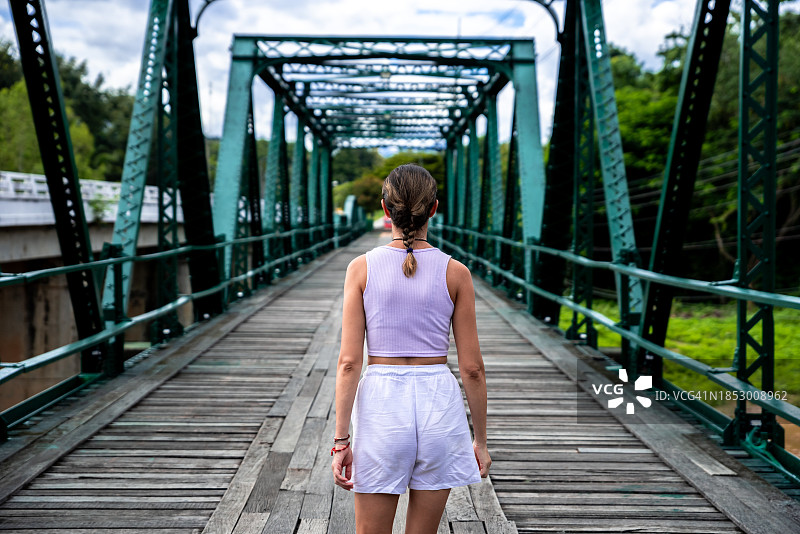 年轻金发女人看着一座绿色桥梁，泰国拜县图片素材