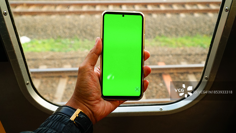 站在通勤列车窗前手持智能手机图片素材