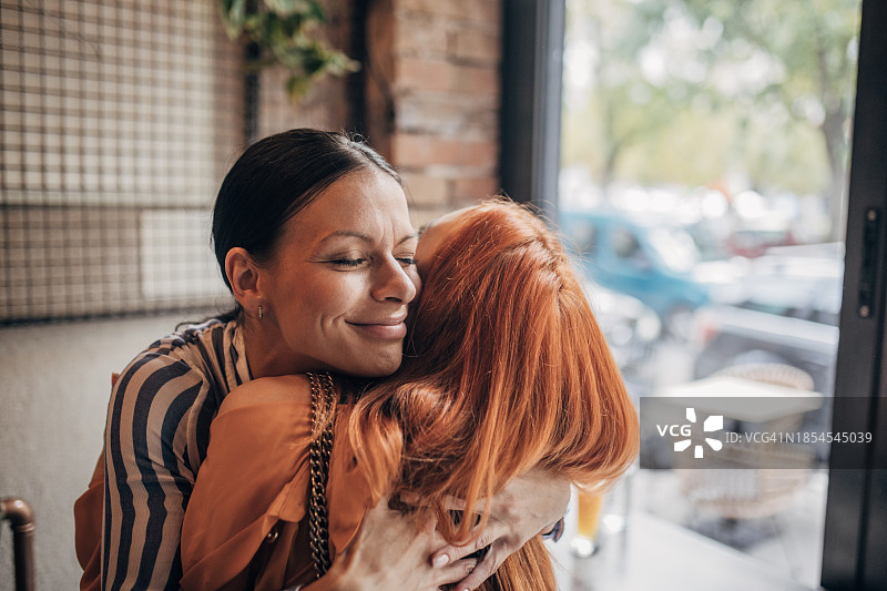 在舒适咖啡馆的友谊拥抱图片素材