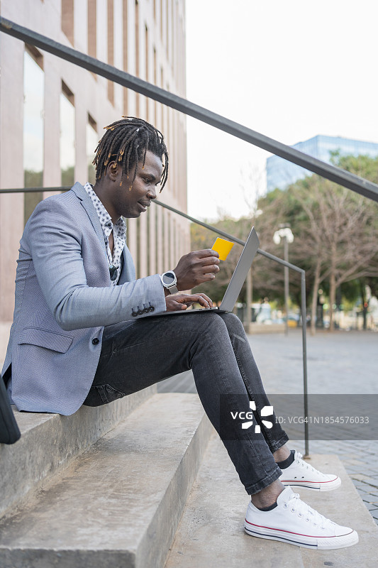 坐在建筑物楼梯上在线购物的商人图片素材