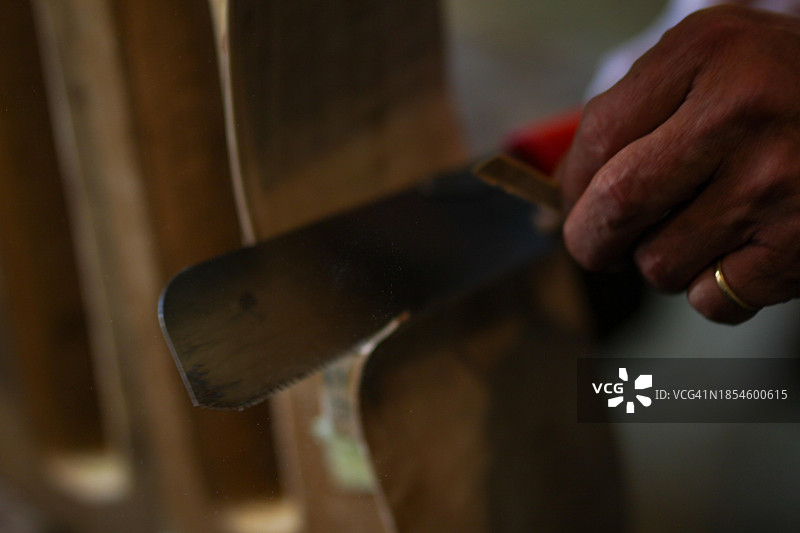 在意大利克雷莫纳，年长的提琴制作师在工作室里拿着凿子图片素材