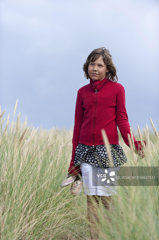 女孩惬意地走过高高的沙丘草地，德国叙尔特岛图片素材