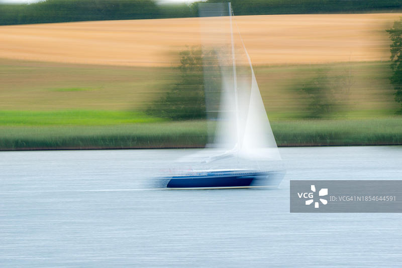 施莱峡的蓝色帆船，背景是芦苇和成熟的谷物田图片素材