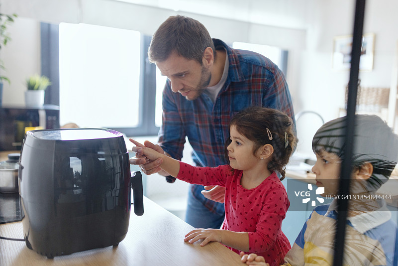 在厨房帮助父亲的可爱女孩图片素材