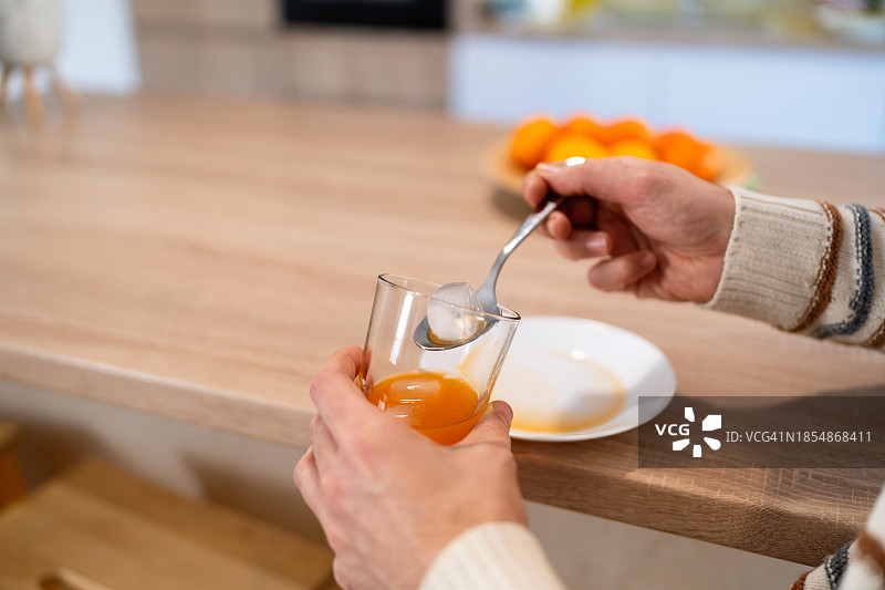男子从橙汁杯中取出冰块特写图片素材