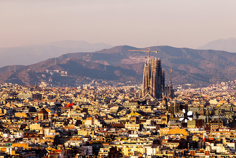 巴塞罗那城市风光：圣家族教堂和日落时分的山脉，西班牙图片素材
