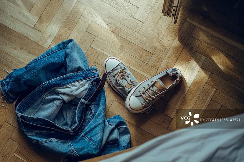 床边地板上的牛仔裤和运动鞋图片素材
