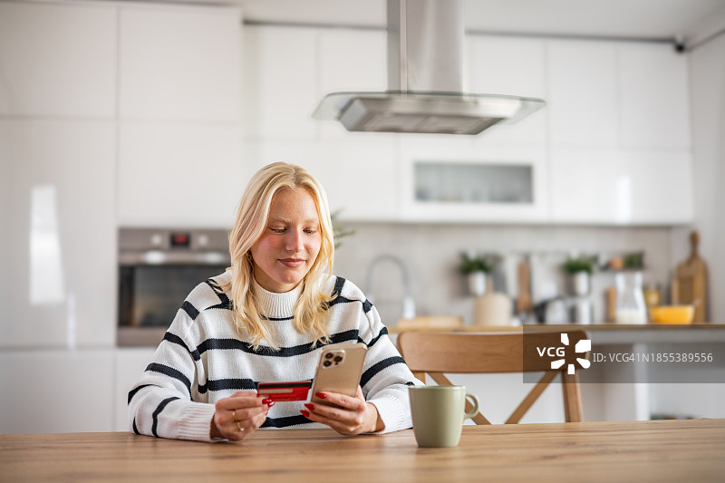 年轻女子在家中使用手机和支付卡进行网上购物图片素材