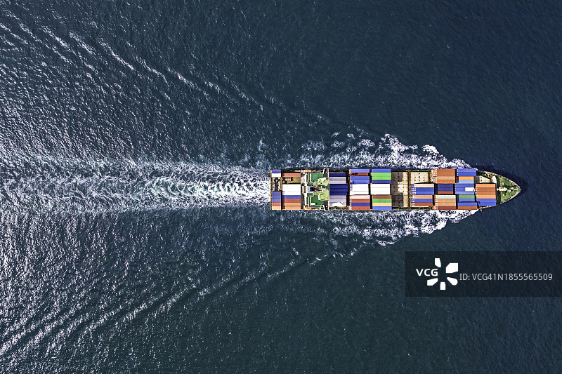 航拍视角：停靠在蓝色海域码头的集装箱货轮，用于进出口物流图片素材