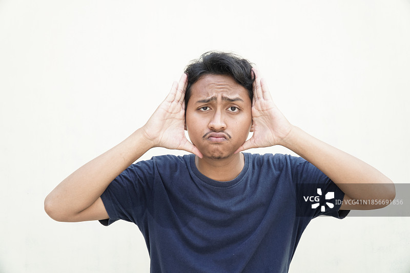 在白色背景上手指脸部的英俊亚洲青年男子图片素材