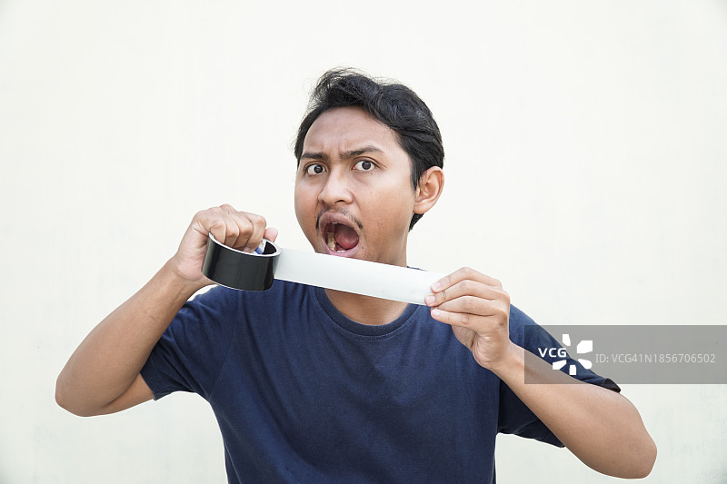 拉扯黑色胶带的惊讶男孩图片素材