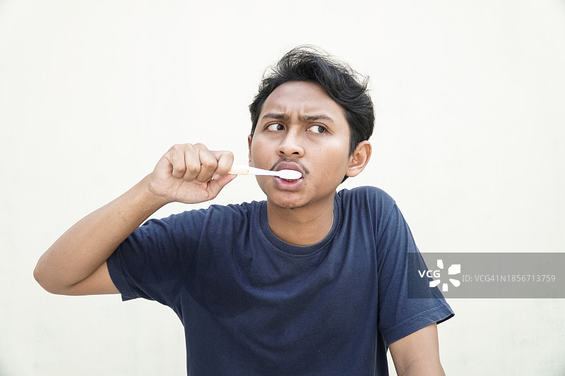 表情严肃的英俊亚洲男模特在刷牙图片素材